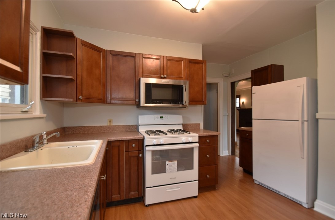 1135 Plainfield Road Cleveland, OH 44121 - Photo 15 of 32 Kitchen featuring white appliances, light wood-type flooring, and sink