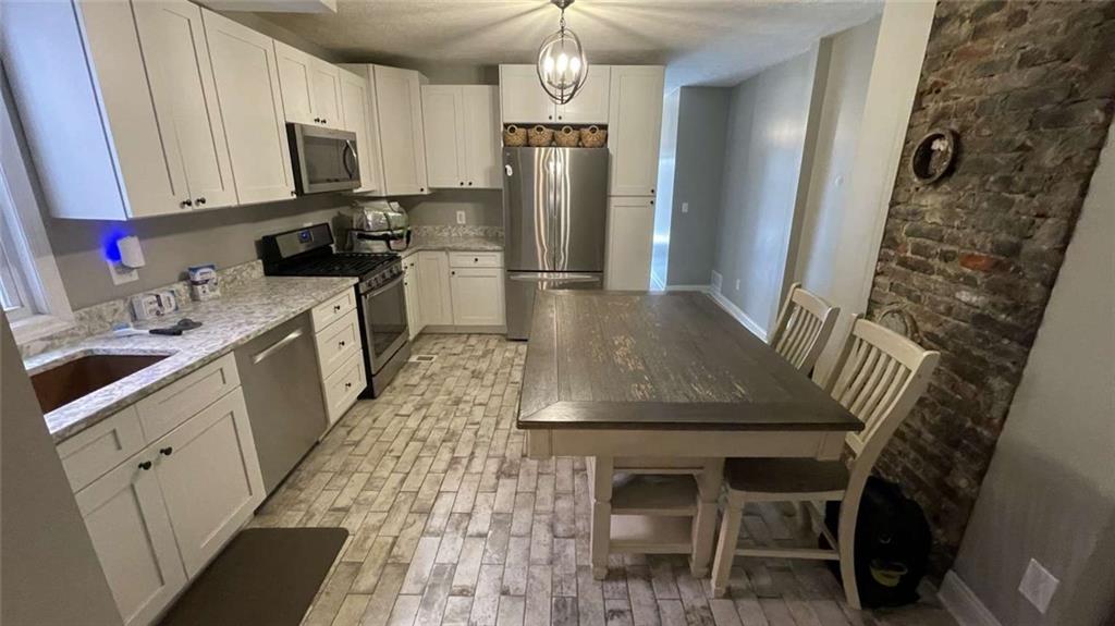 615 Tripoli Street Pittsburgh, PA 15212 - Photo 5 of 25 a kitchen with stainless steel appliances granite countertop a sink dishwasher stove a refrigerator and a dining table with wooden floor