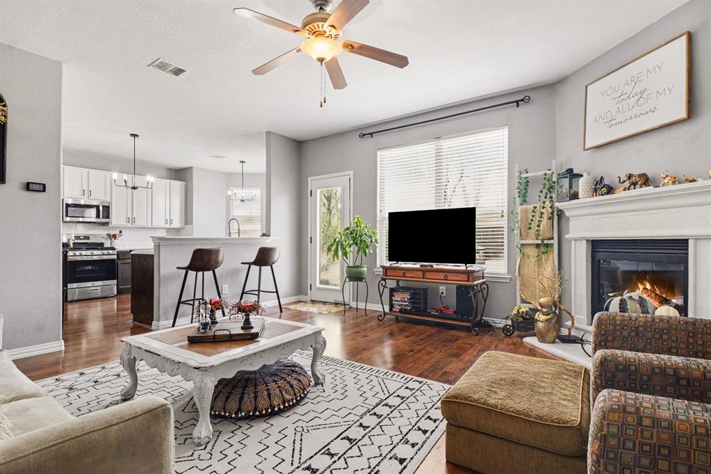 10005 Turrey Rowlett, TX 75089 - Photo 14 of 32 Living room with ceiling fan, dark wood-style floors, a glass covered fireplace, and hanging lights