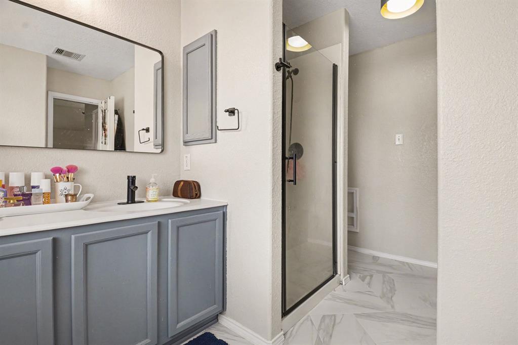 10005 Turrey Rowlett, TX 75089 - Photo 19 of 32 Bathroom with vanity, a shower stall, a textured wall, and light marble finish floors