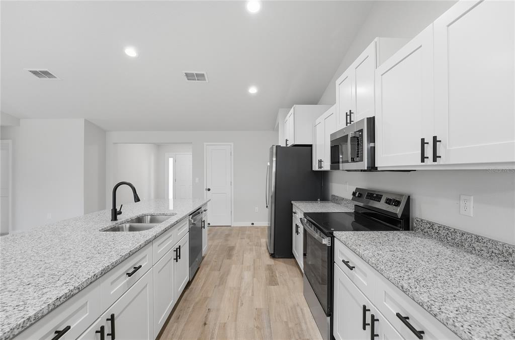 13161 Southwest 60th Avenue Ocala, FL 34473 - Photo 14 of 36 a kitchen with granite countertop a sink stove and refrigerator
