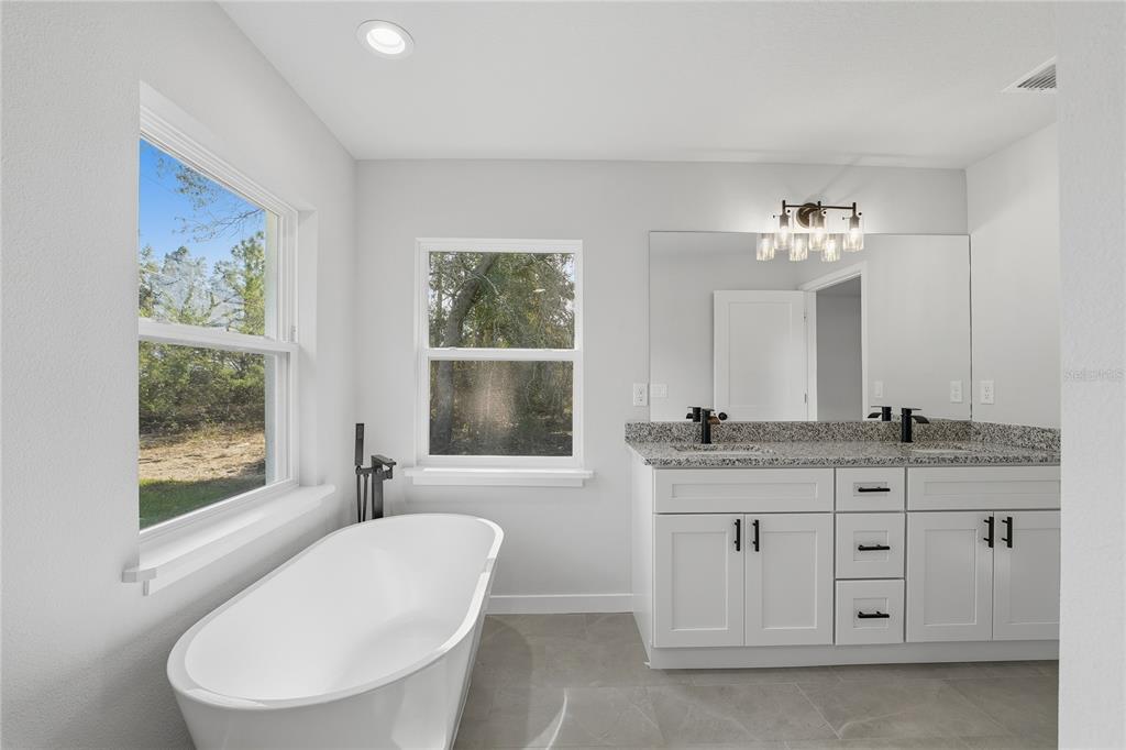 13161 Southwest 60th Avenue Ocala, FL 34473 - Photo 23 of 36 a bathroom with a granite countertop toilet a sink and a large mirror