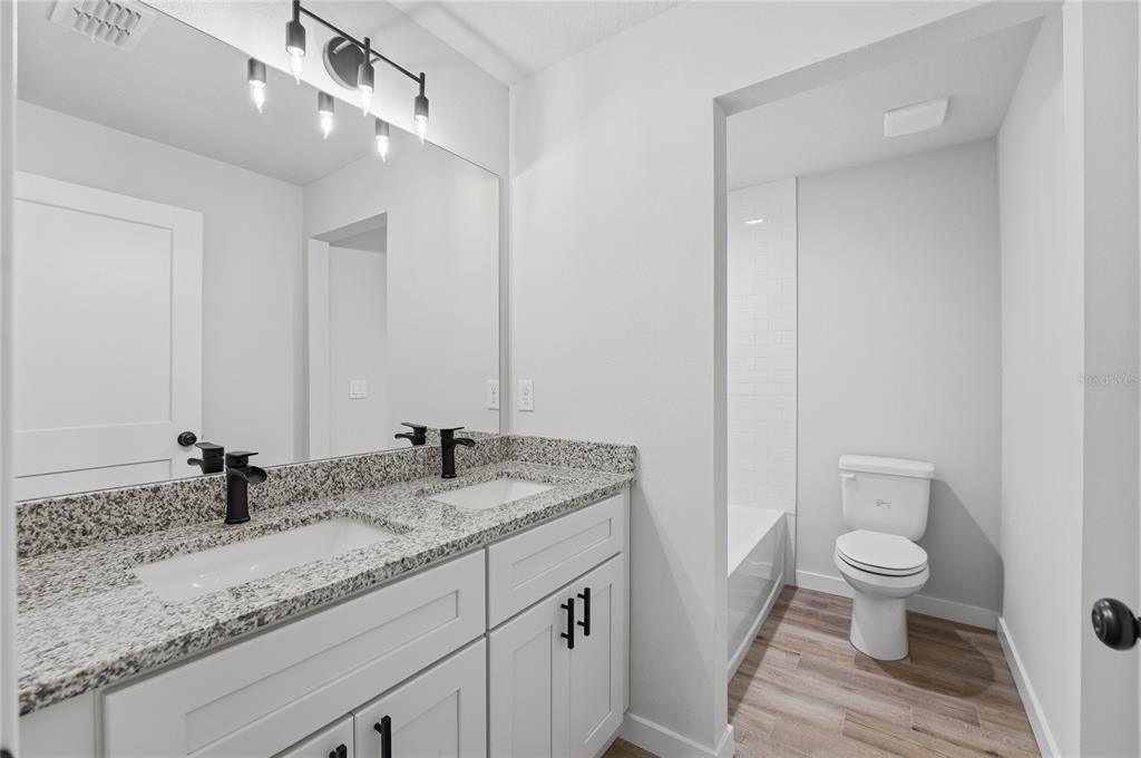 13161 Southwest 60th Avenue Ocala, FL 34473 - Photo 25 of 36 a bathroom with a granite countertop sink a toilet and a mirror