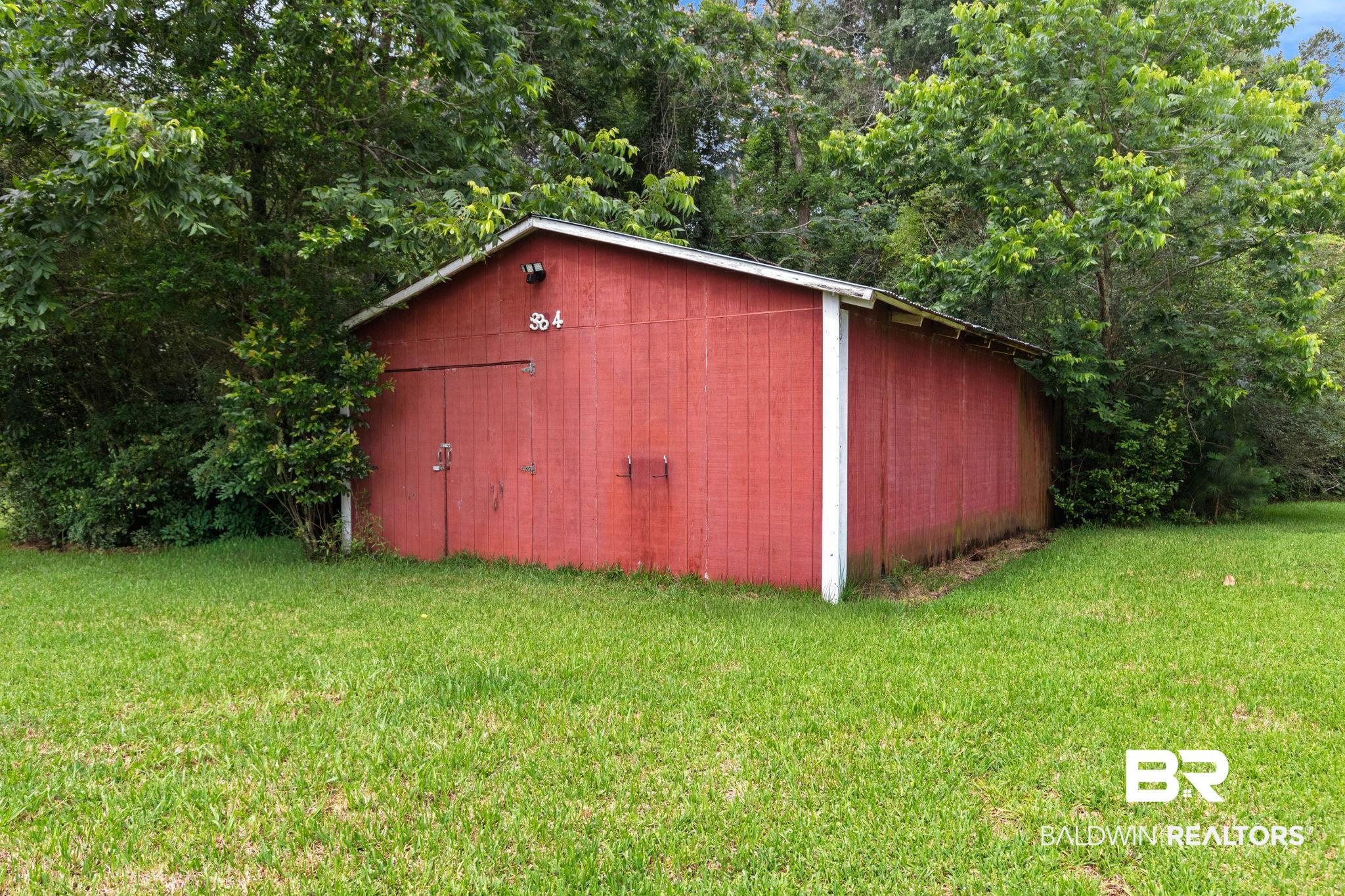 384 Old Bratt Road Atmore, AL 36502 - Photo 63 of 64 Red wood-sided outbuilding featuring a white trim, double entry doors, a single window opening, and a sloped roofline