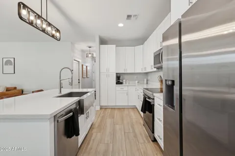 a kitchen with stainless steel appliances a sink dishwasher a refrigerator and a stove with wooden floor