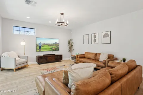 a living room with furniture a flat screen tv and a chandelier
