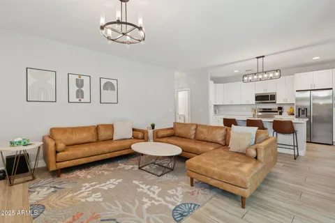 a living room with furniture kitchen view and a chandelier