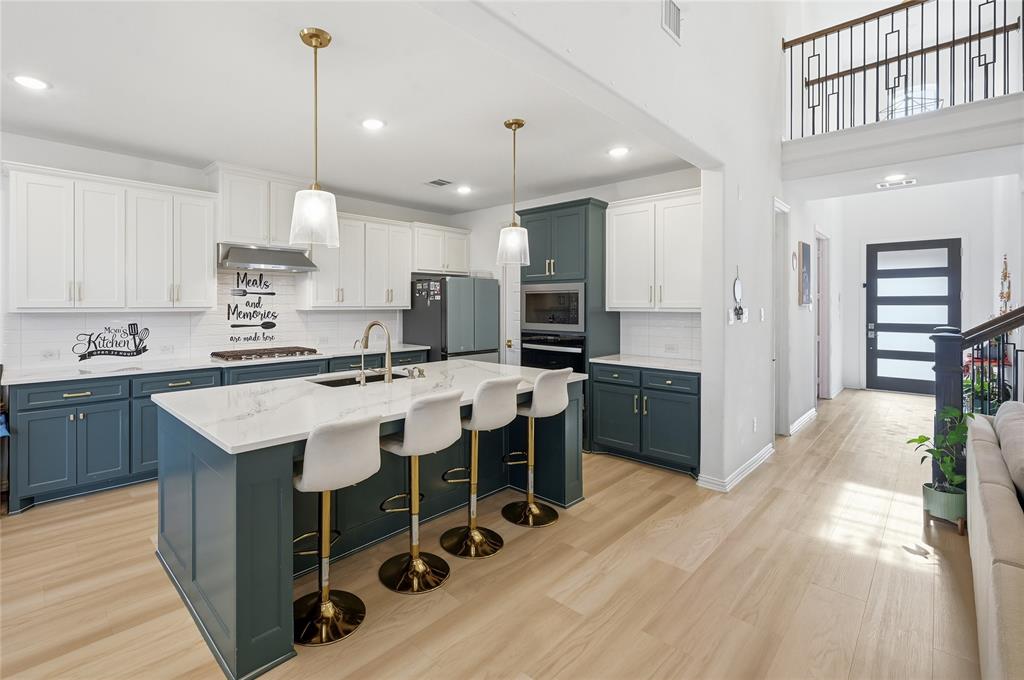 2188 Cloverfern Way Haslet, TX 76052 - Photo 2 of 30 a large kitchen with kitchen island a island a stove a sink a center island and a wooden floor