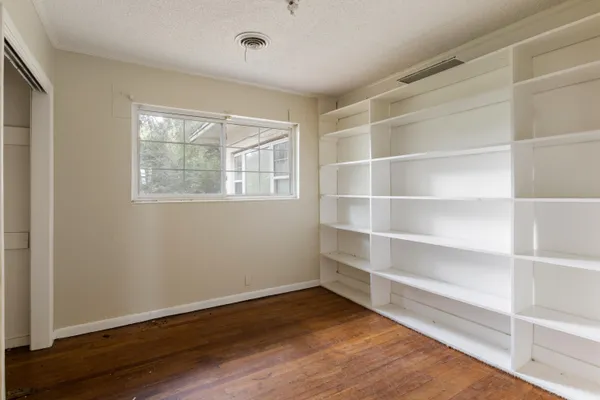 a view of an empty room with a window and wooden floor