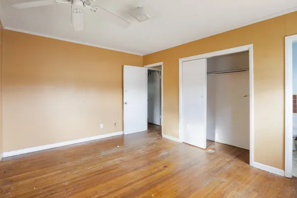 a view of an empty room with wooden floor and closet