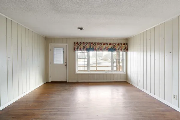 an empty room with wooden floor and windows with curtains view