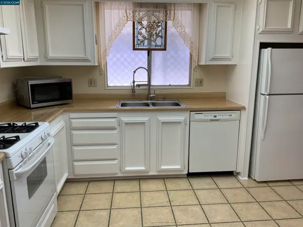 a kitchen with white cabinets a sink stove and refrigerator