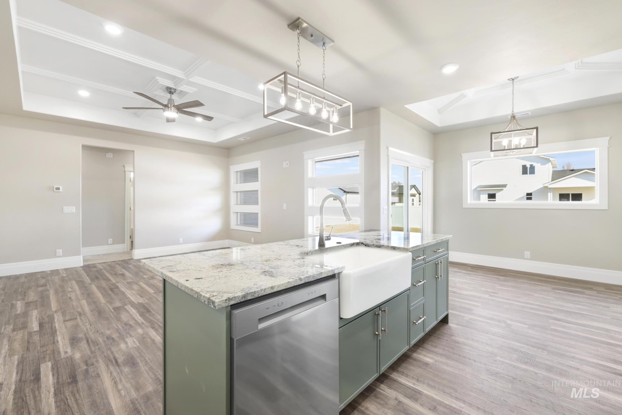 1316 K Street Rupert, ID 83350 - Photo 9 of 44 Kitchen with dishwasher, a tray ceiling, dark wood-style floors, light stone countertops, and a kitchen island with sink