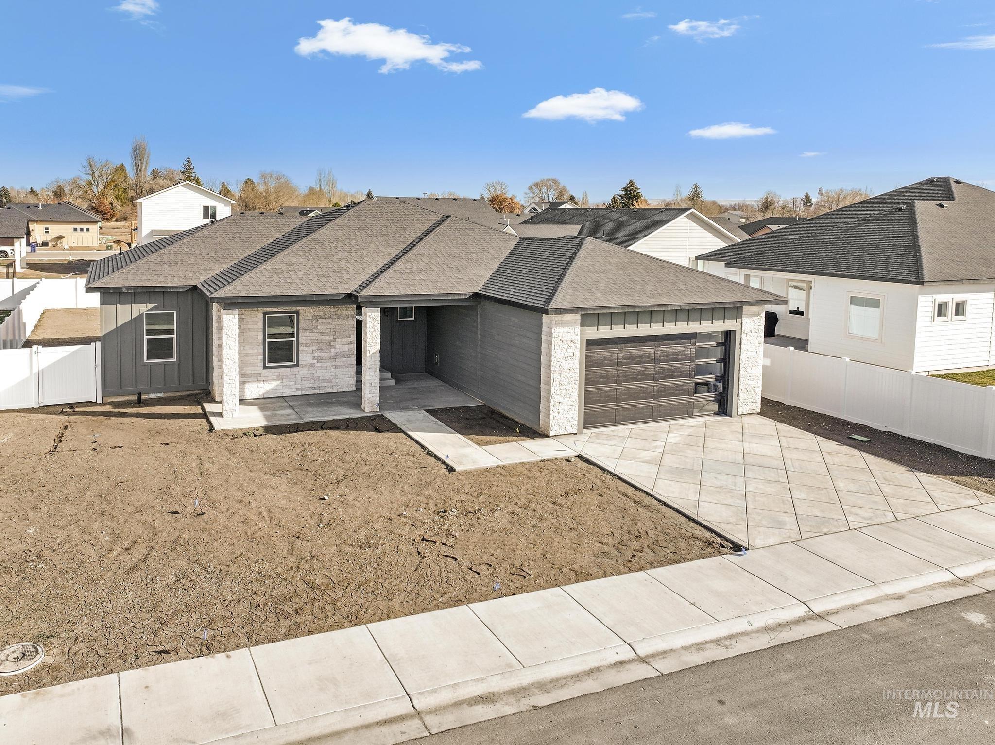 1316 K Street Rupert, ID 83350 - Photo 31 of 44 View of front of property featuring roof with shingles, concrete driveway, an attached garage, a residential view, and board and batten siding