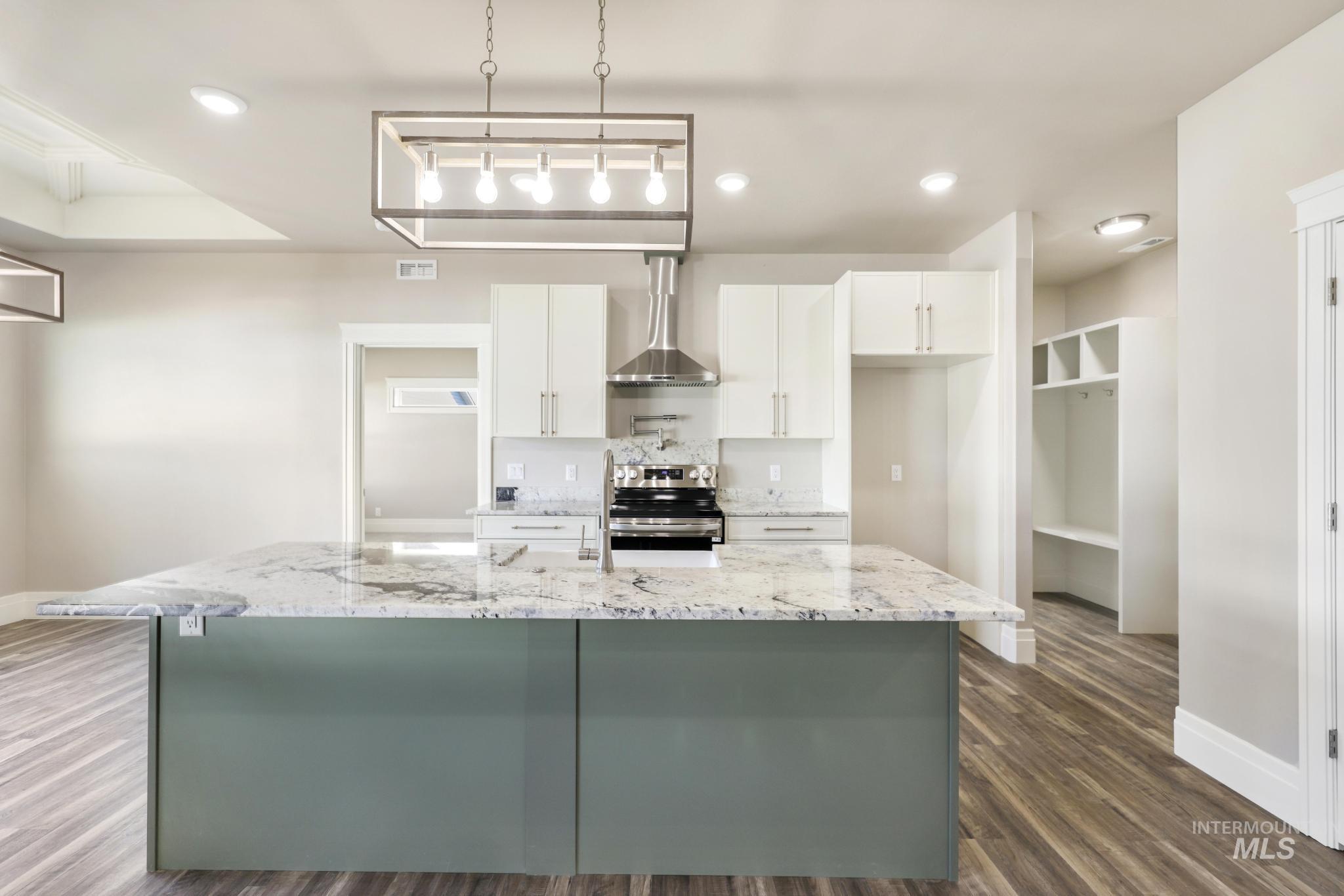 1316 K Street Rupert, ID 83350 - Photo 6 of 44 Kitchen featuring dark wood finished floors, electric stove, light stone counters, hanging light fixtures, and an island with sink