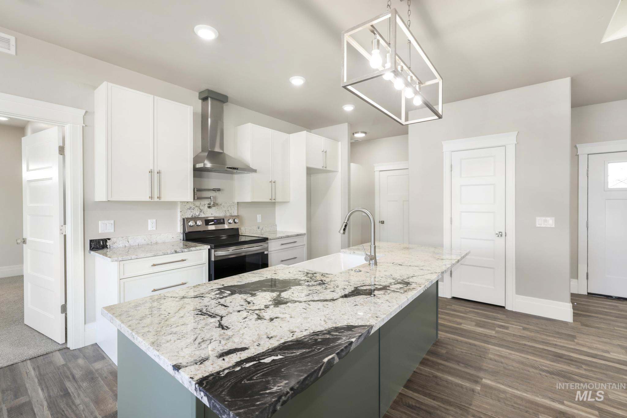 1316 K Street Rupert, ID 83350 - Photo 7 of 44 Kitchen featuring electric stove, light stone counters, a kitchen island with sink, suspended lighting, and dark wood-style floors