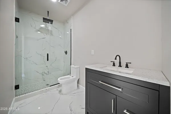 a bathroom with a granite countertop sink a toilet and shower