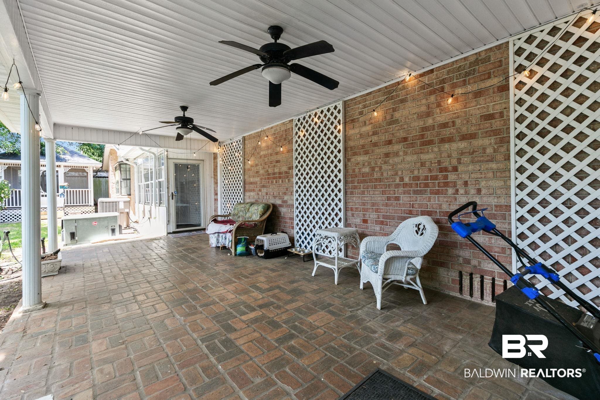 927 Cleveland Road Saraland, AL 36571 - Photo 55 of 80 Covered patio featuring brick paver flooring, a white paneled ceiling, and two black ceiling fans
