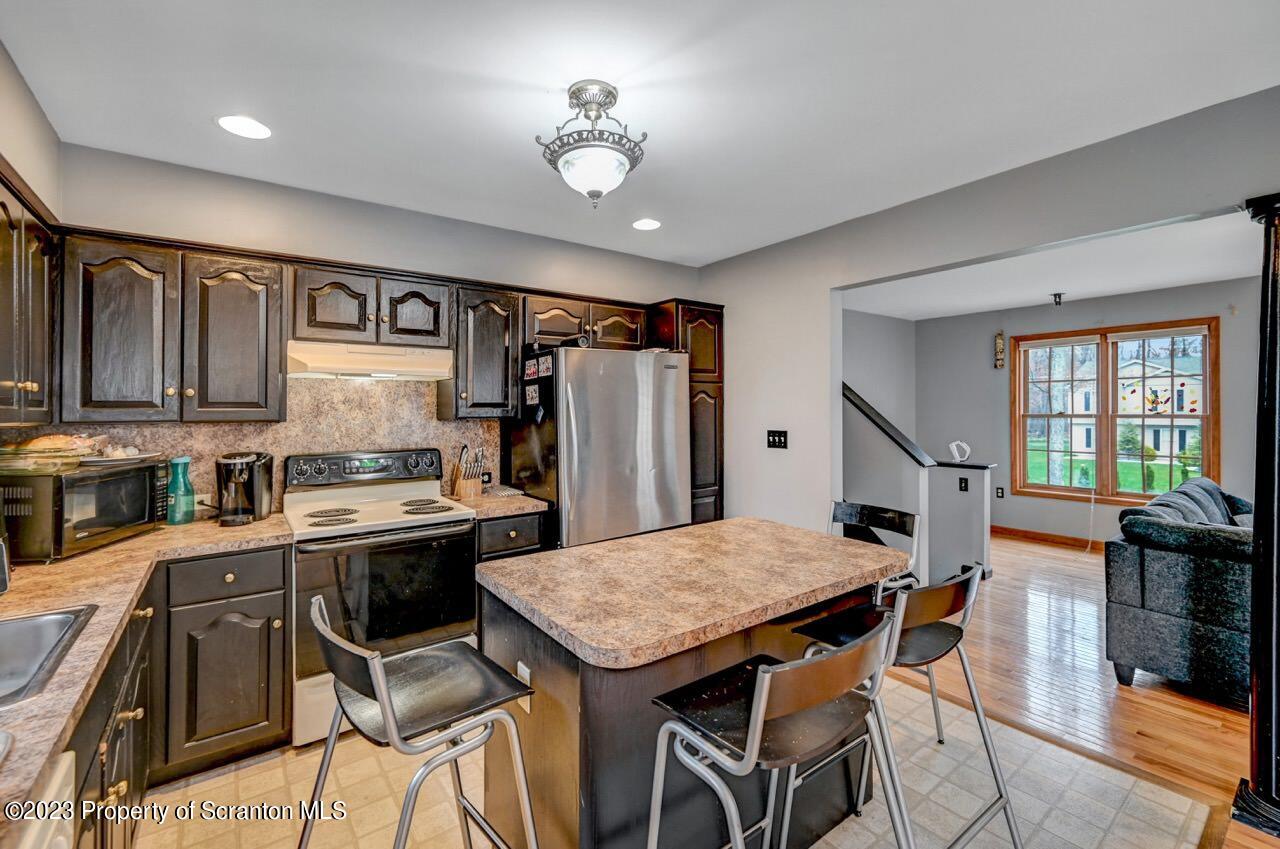 4156 Romeo Road Tobyhanna, PA 18466 - Photo 16 of 46 a kitchen with stainless steel appliances granite countertop a stove a refrigerator a sink dishwasher a dining table and chairs with wooden floor