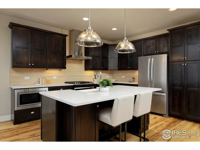 a kitchen with stainless steel appliances a stove a refrigerator a sink a dining table and chairs