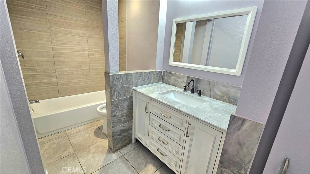 7641 Reseda Boulevard, Unit 87 Reseda, CA 91335 - Photo 20 of 37 a bathroom with a granite countertop double vanity sink a mirror and a bathtub