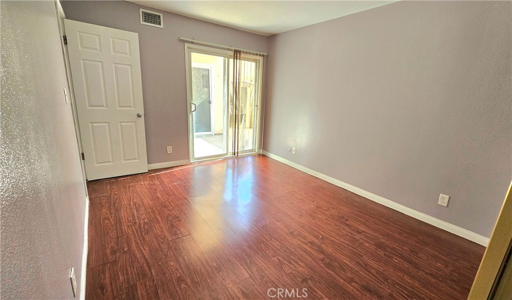 7641 Reseda Boulevard, Unit 87 Reseda, CA 91335 - Photo 22 of 37 a view of an empty room with wooden floor and a window