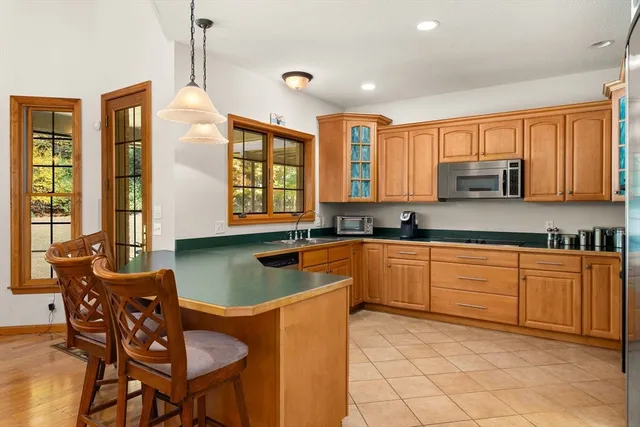 a kitchen with stainless steel appliances granite countertop a stove a sink dishwasher a dining table and chairs with wooden floor