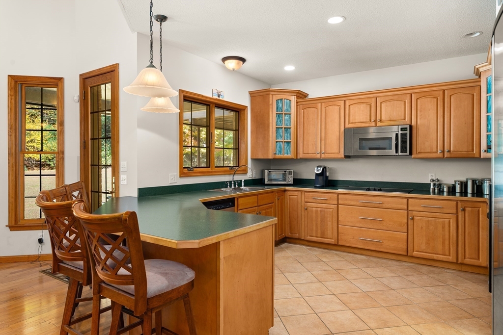 59 St Germain Road Hampden, MA 01036 - Photo 21 of 42 a kitchen with stainless steel appliances granite countertop a stove a sink dishwasher a dining table and chairs with wooden floor