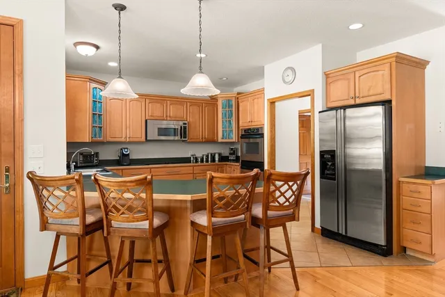 a kitchen with stainless steel appliances granite countertop a refrigerator a stove a kitchen island with a dining table and chairs