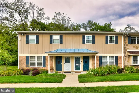 a front view of a house with garden and trees