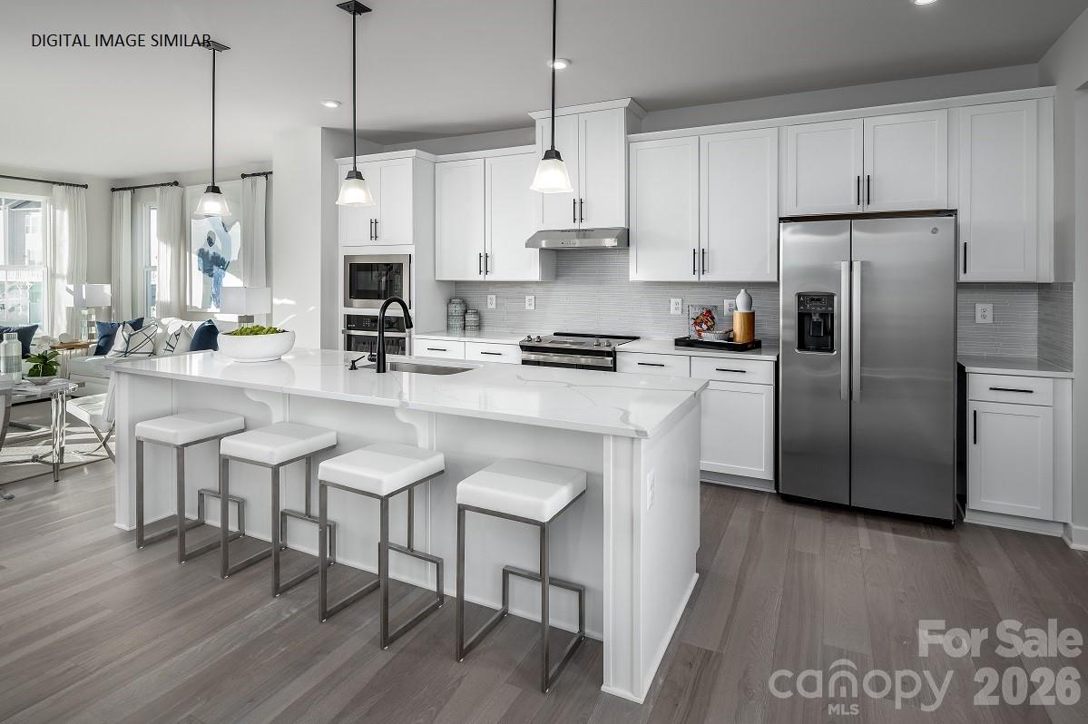 2287 Flicker Road, Unit 1050A Indian Land, SC 29707 - Photo 2 of 13 a kitchen with stainless steel appliances granite countertop a refrigerator a stove a sink a dining table and chairs with wooden floor