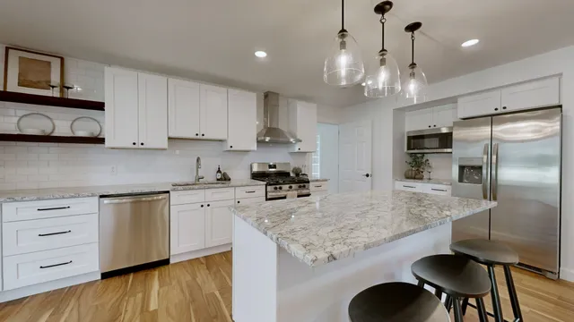 a kitchen with kitchen island granite countertop stainless steel appliances a sink stove and refrigerator