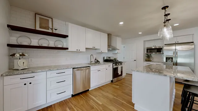a kitchen with granite countertop kitchen island stainless steel appliances a sink a stove and cabinets