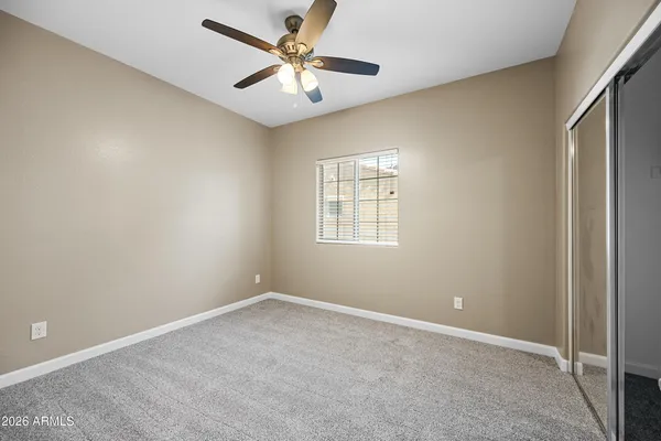 an empty room with a window and a ceiling fan