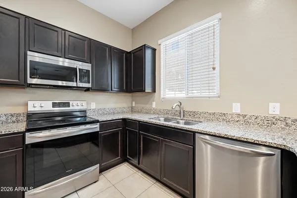 a kitchen with granite countertop cabinets stainless steel appliances a sink and a window