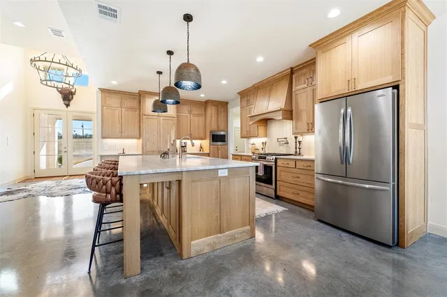 a kitchen with stainless steel appliances granite countertop a refrigerator a oven a sink a dining table and chairs with wooden floor