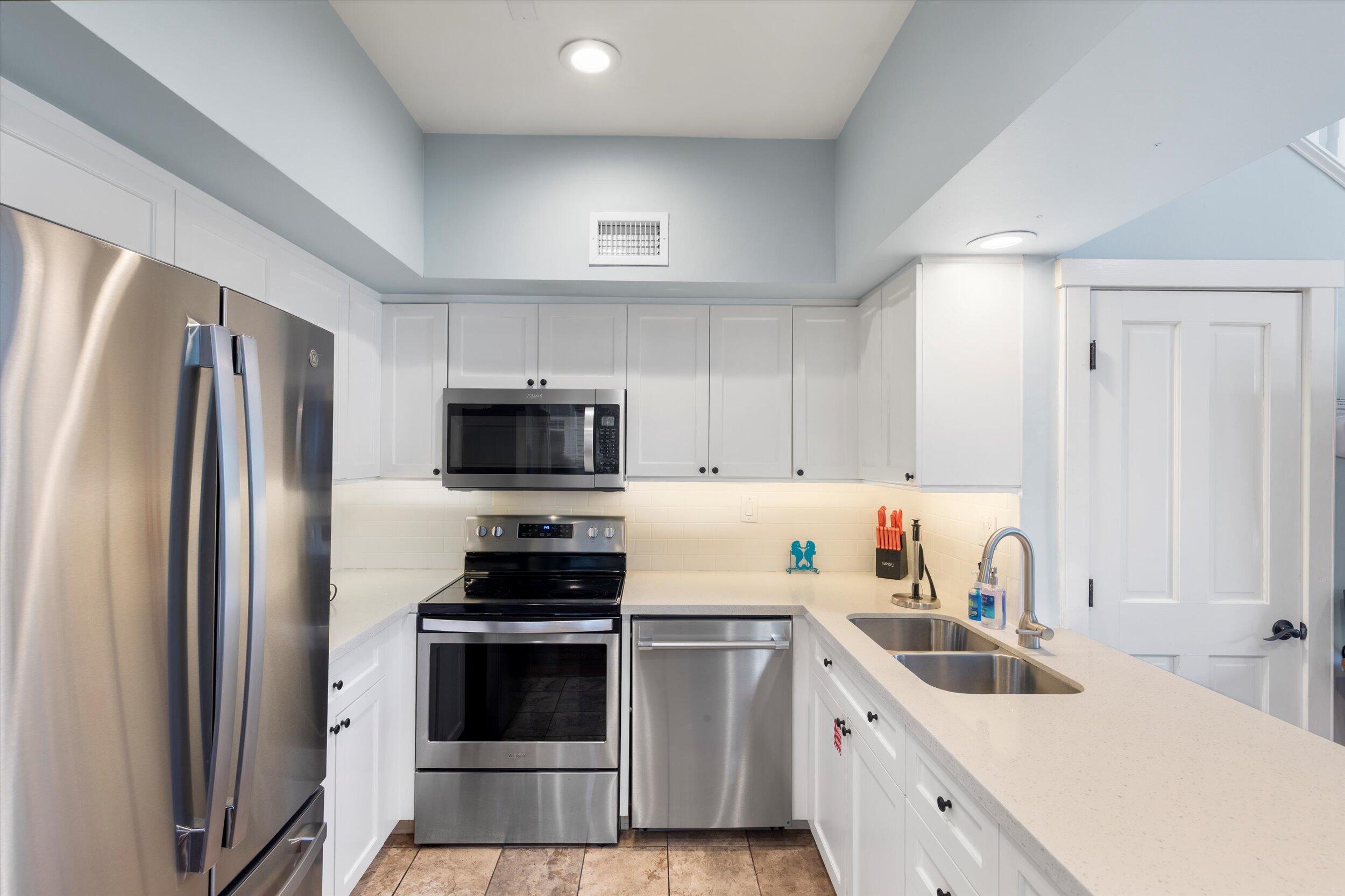 606 Truman Avenue, Unit 7 Key West, FL 33040 - Photo 11 of 49 a kitchen with refrigerator a sink and white cabinets