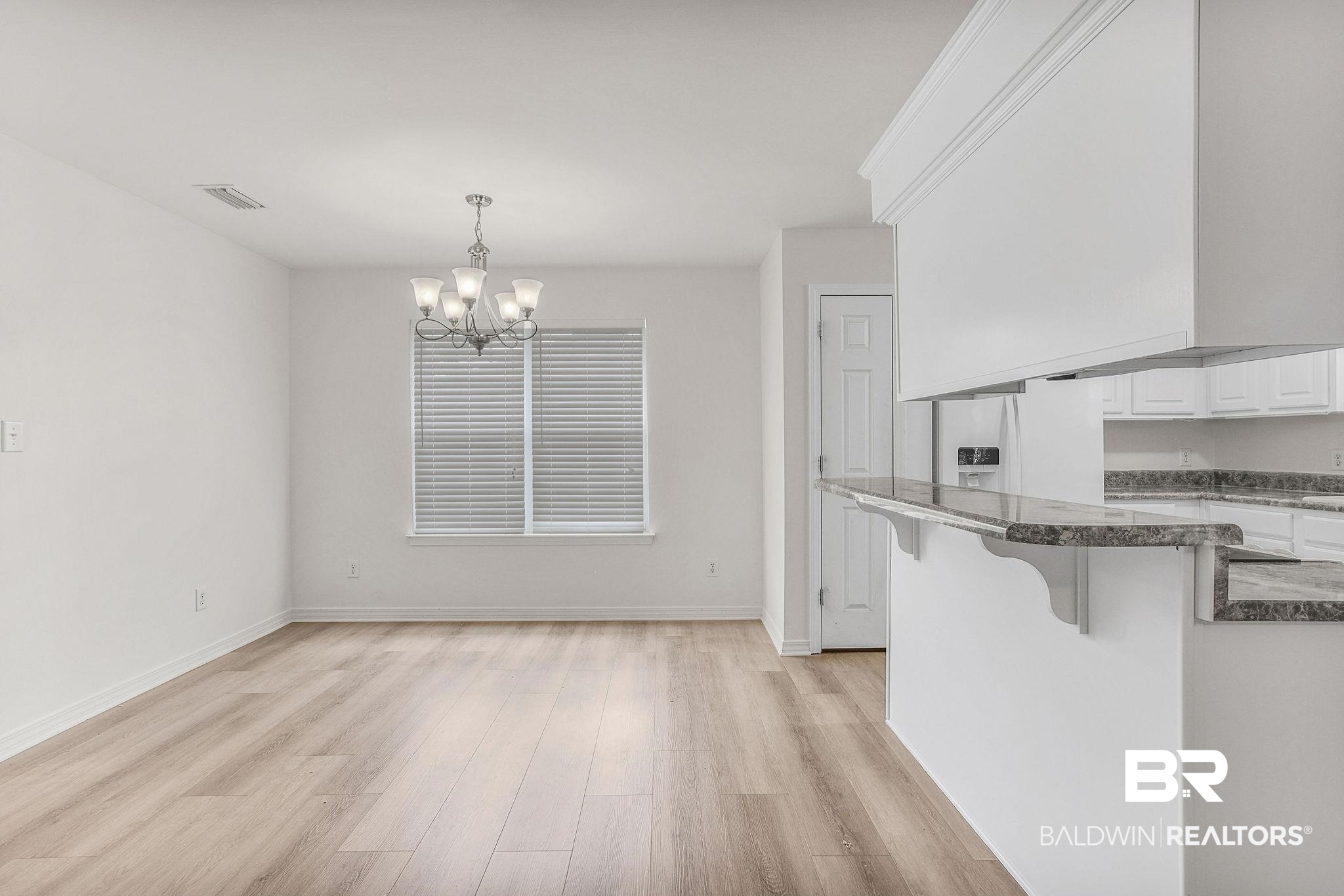 18620 Hammond Street Robertsdale, AL 36567 - Photo 7 of 23 Kitchen featuring an inviting chandelier, light hardwood / wood-style flooring, a breakfast bar, and white cabinets