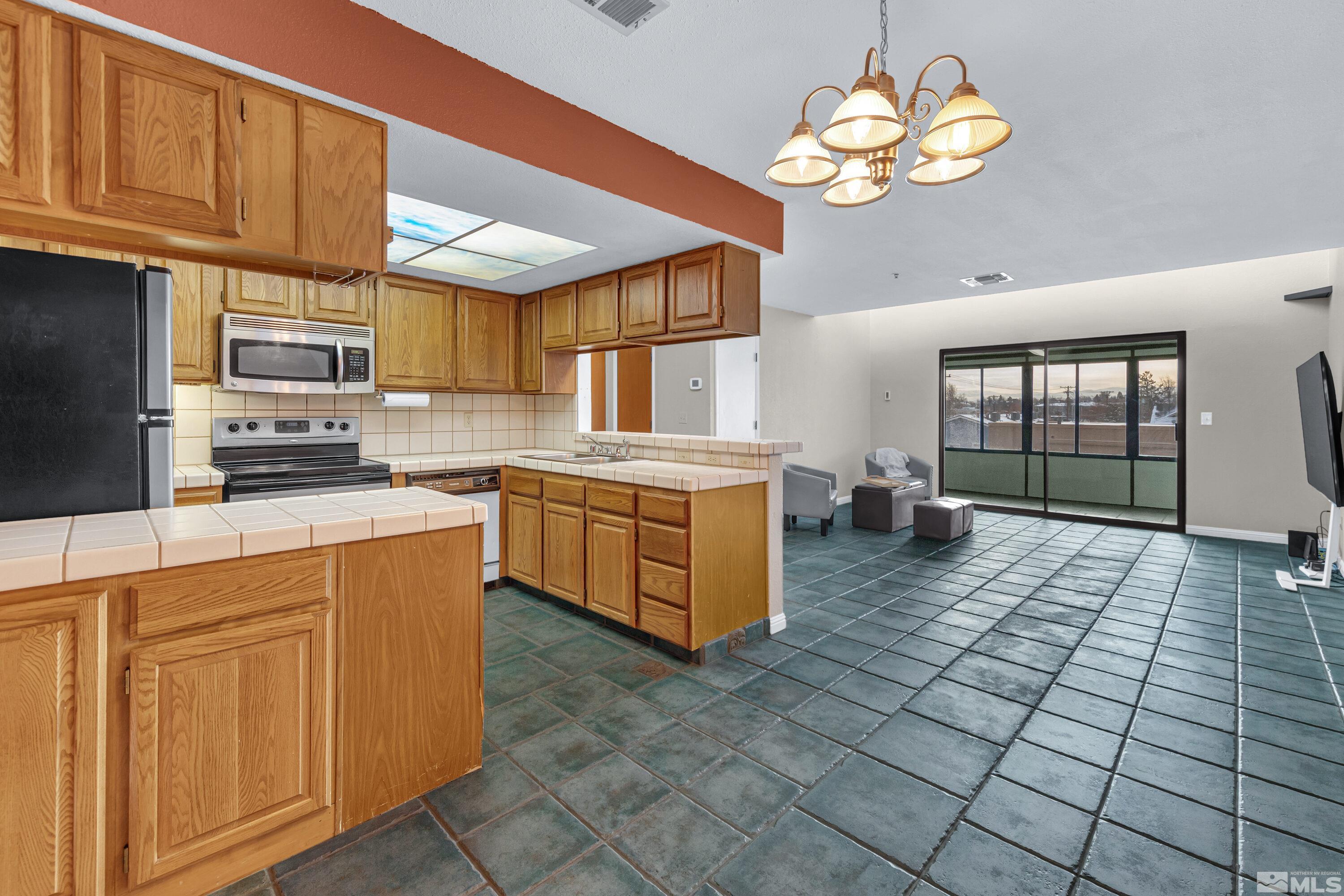 3095 Lakeside Drive, Unit 304 Reno, NV 89509 - Photo 1 of 38 a kitchen with stainless steel appliances granite countertop a stove a sink dishwasher and white cabinets with wooden floor
