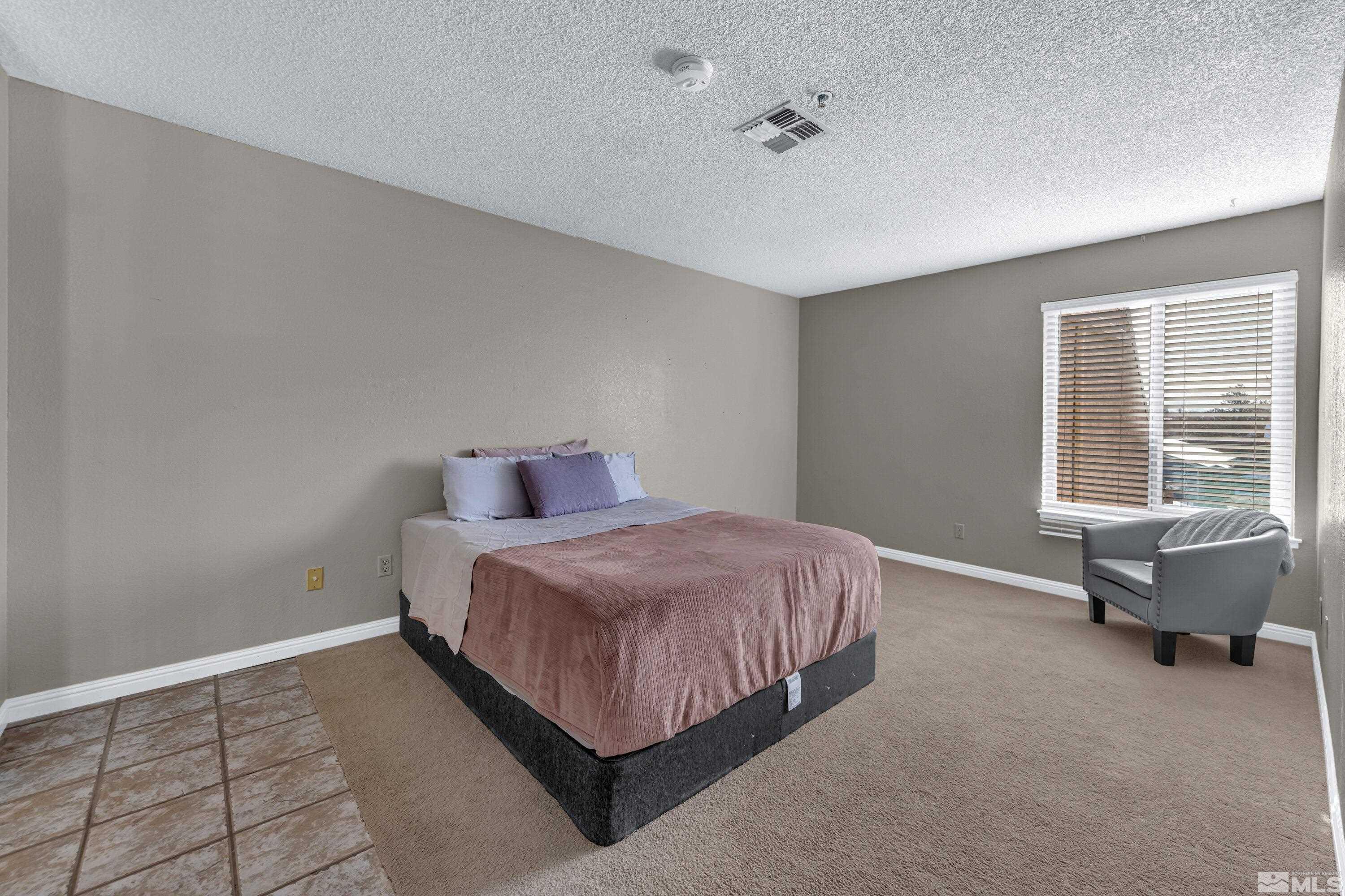 3095 Lakeside Drive, Unit 304 Reno, NV 89509 - Photo 14 of 38 a spacious bedroom with a bed and a chandelier