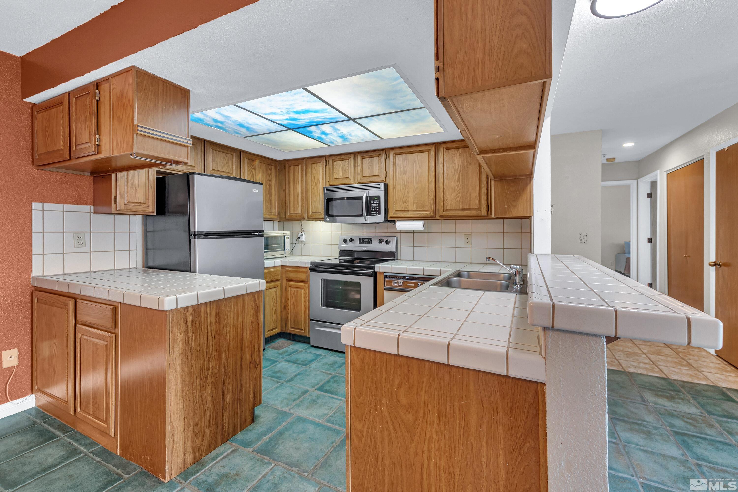 3095 Lakeside Drive, Unit 304 Reno, NV 89509 - Photo 4 of 38 a kitchen with stainless steel appliances granite countertop a stove top oven a sink dishwasher and a refrigerator with wooden cabinets