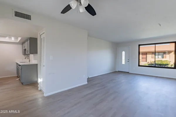 an empty room with wooden floor cabinet and windows