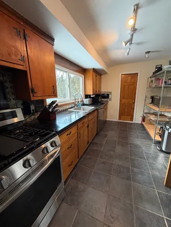 a large kitchen with stainless steel appliances granite countertop a stove a sink and a microwave