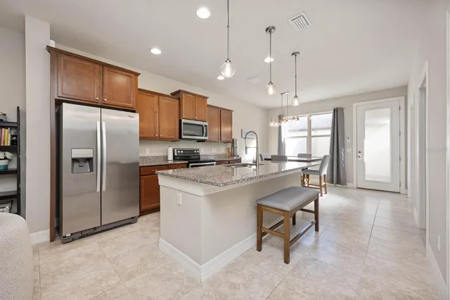 a kitchen with stainless steel appliances granite countertop a refrigerator a sink dishwasher a stove and a refrigerator with wooden floor