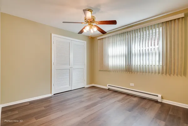 an empty room with wooden floor chandelier fan and windows