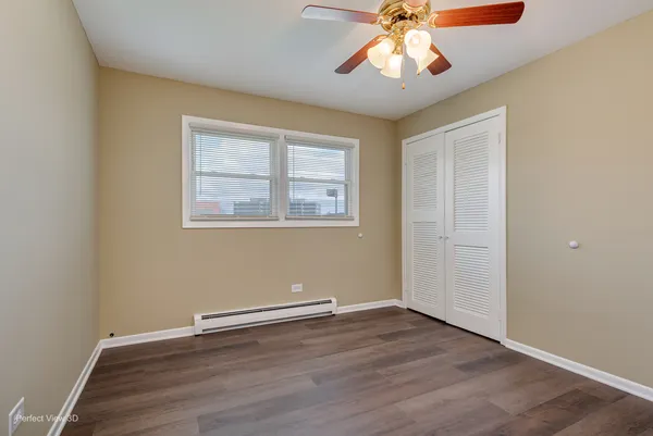 an empty room with wooden floor chandelier fan and windows