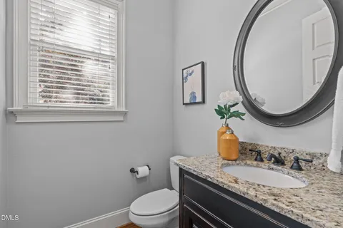 a bathroom with a granite countertop toilet a sink and a mirror