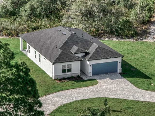 a aerial view of a house next to a big yard and large trees