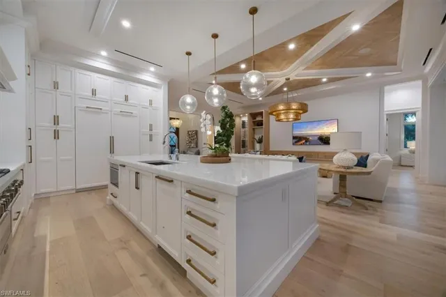a large white kitchen with a large island oven a stove and white cabinets
