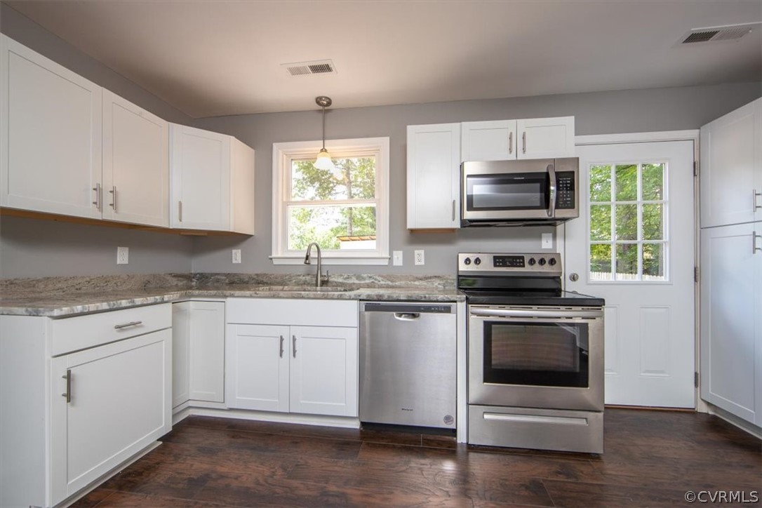 9301 Telstar Drive Richmond, VA 23237 - Photo 6 of 24 a kitchen with granite countertop white cabinets appliances a sink and a window